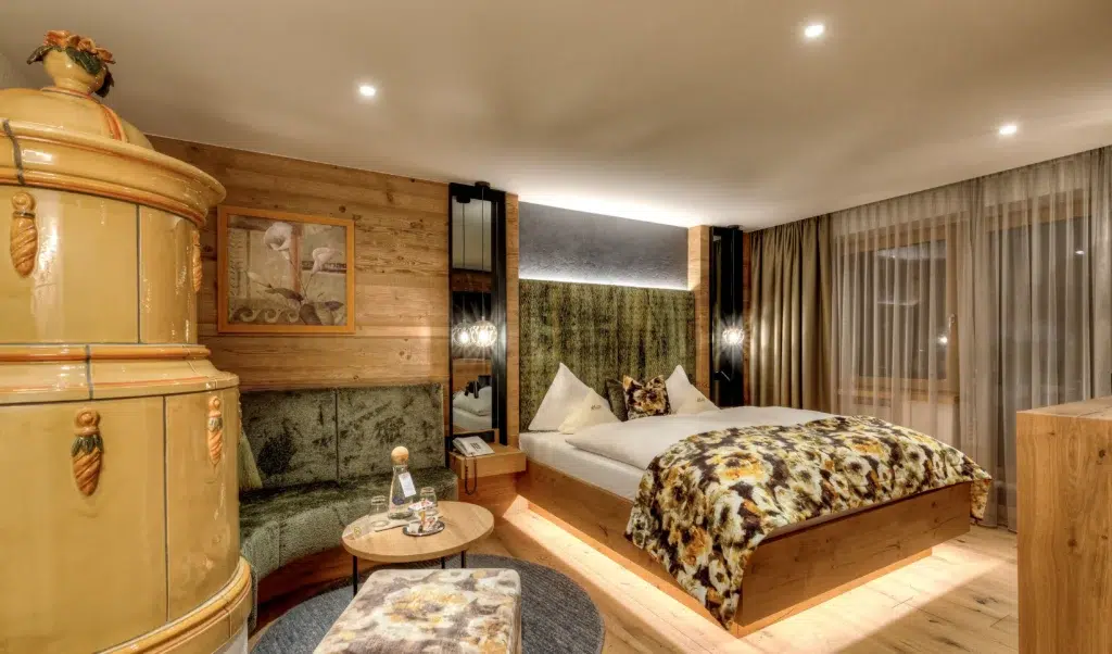 Gemütliches Zimmer der Suite Ischgl mit Doppelbett, Holzdekor, gemustertem Bettzeug und warmer Beleuchtung.